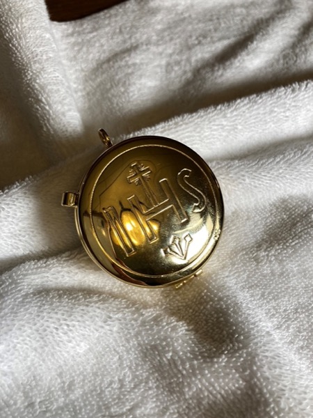 The pyx – A small circular vessel that opens and closes and holds the Holy Eucharist. This is used by Priests, Deacons, and Extraordinary Ministers of Holy Communion when traveling to distribute the Eucharist somewhere in the community. Its name comes from a Latin word meaning a box.