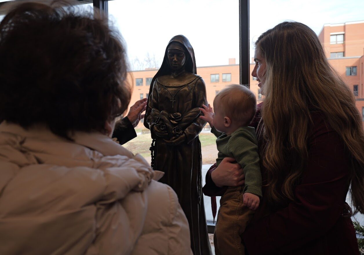 The son of Riley Root, the sculptor of the newly blessed Mother M. Anselma, touches the fruit of his mother's labor after it was blessed by Bishop Paprocki.

<br><em>
Photo by Sister M. Consolata Crews, FSGM</em>