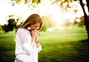 A closeup shot of a female praying with a blurred background